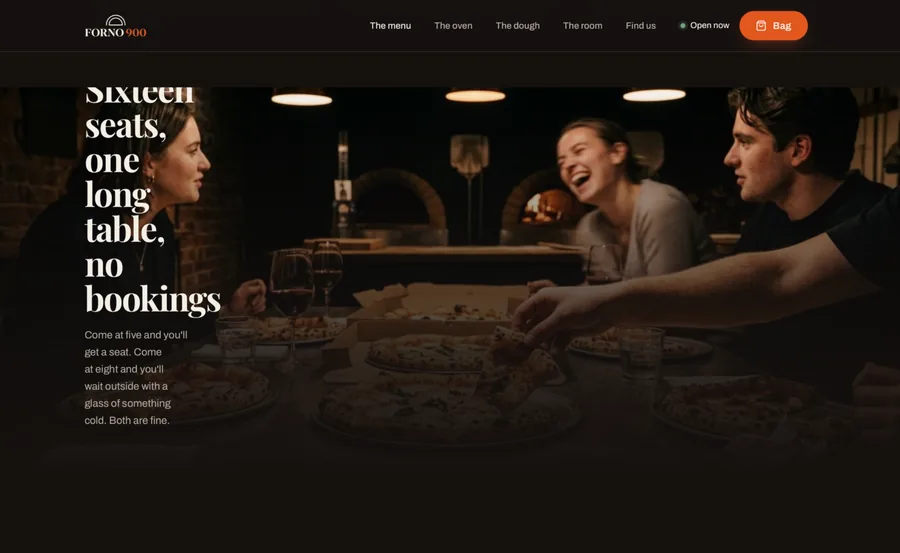 FORNO 900 full-bleed room section: a photograph of guests laughing around a long table of pizzas, with the headline &ldquo;Sixteen seats, one long table, no bookings&rdquo; set into the image